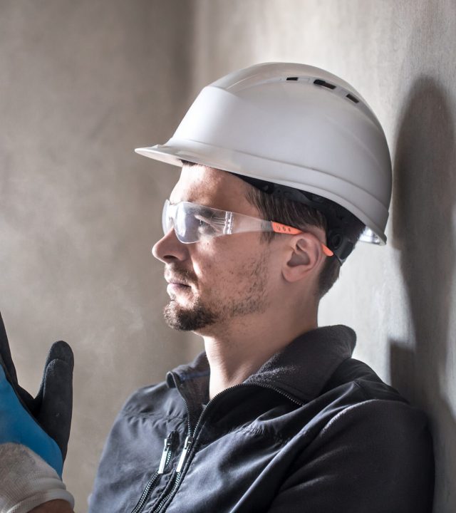 Man, an electrical technician working in a switchboard with fuses. Installation and connection of electrical equipment. Professional with tools in hand. concept of complex work, space for text.